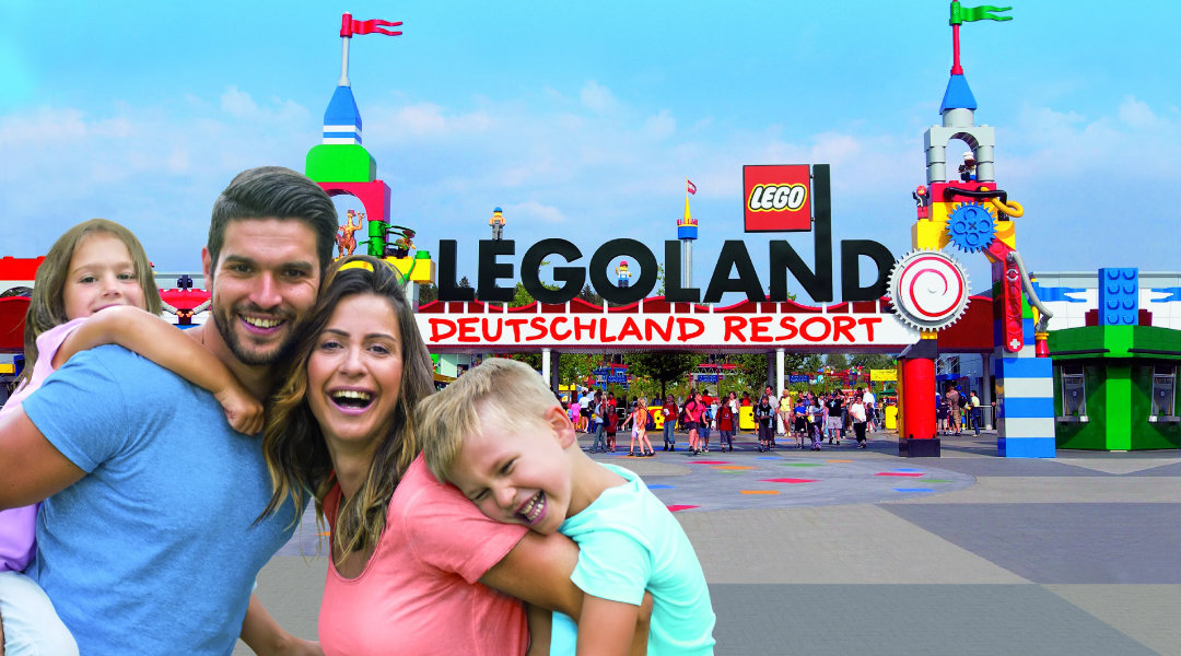 Eine Familie lächelt und im Hintergrund erkennt man das Legoland Deutschland Resort.